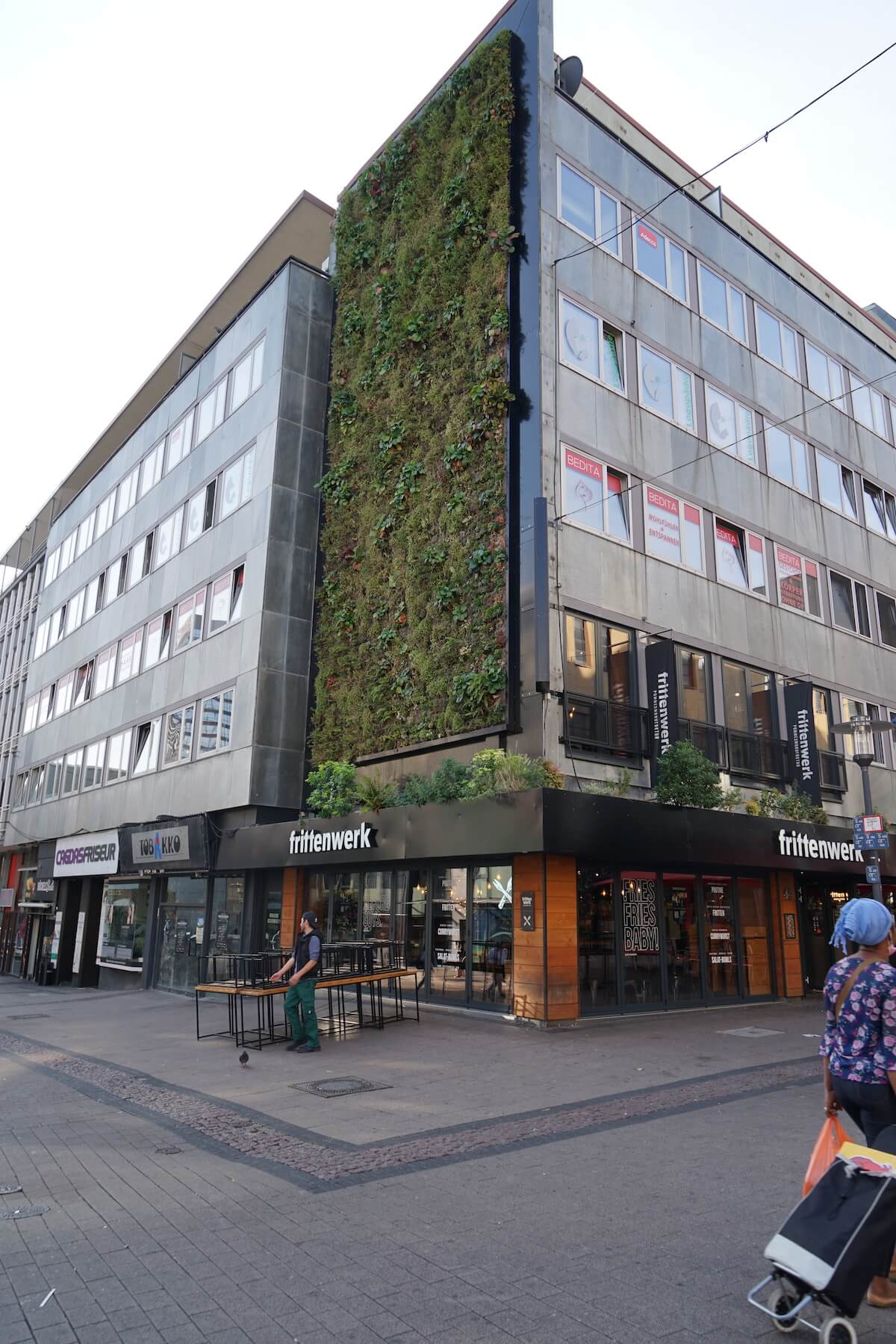 Ein Gebäude mit einer begrünten Fassade in einer Fußgängerzone.