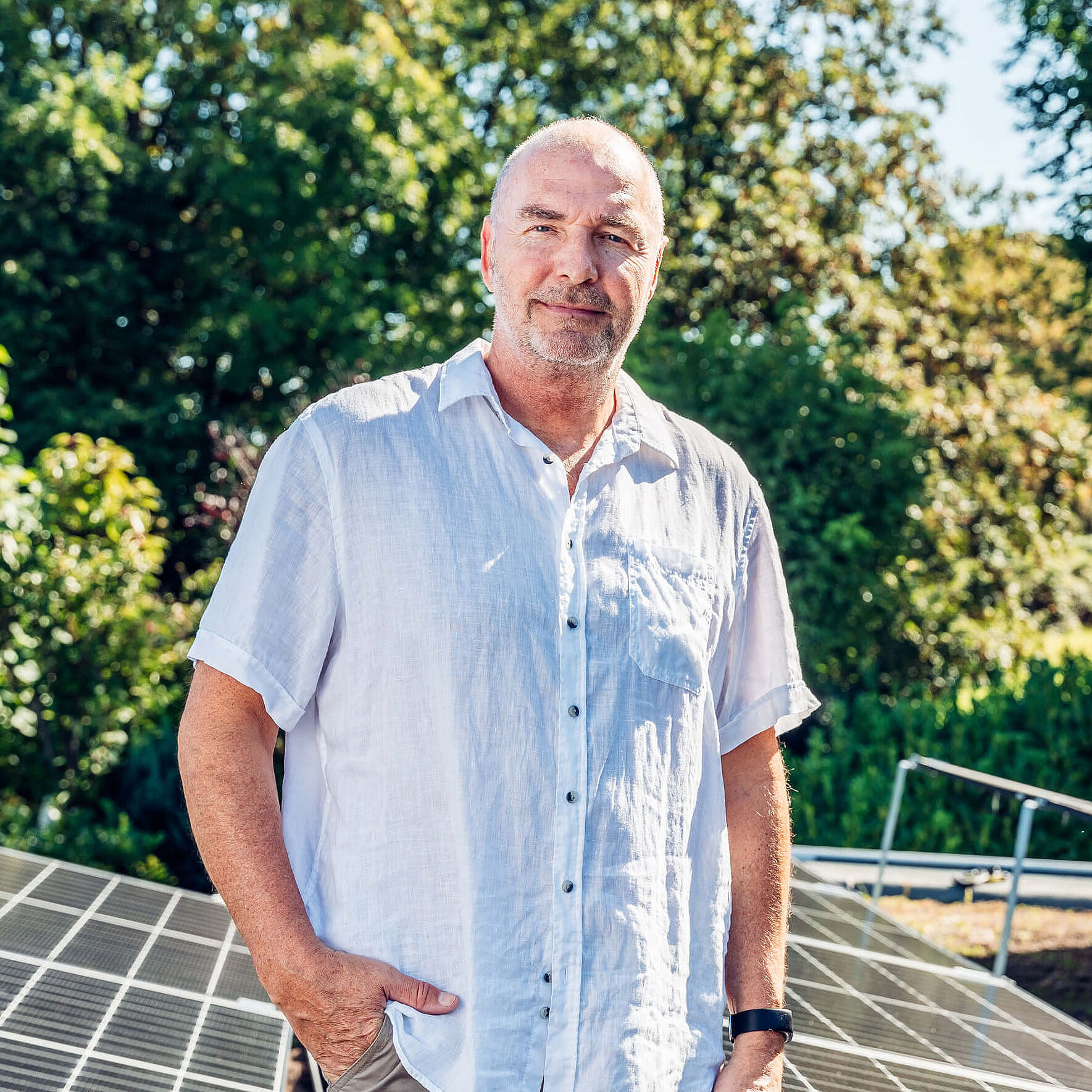 Dirk Wiese steht auf seinem begrünten Dach. Im Hintergrund sieht man die Solaranlagen.